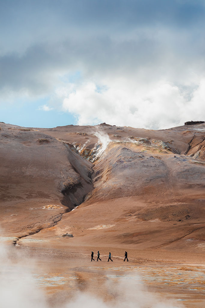 Landschapsfoto van vier mensen die lopen door de lavevelden van Hverir in IJsland, door reisfotograaf Moments by Mark.