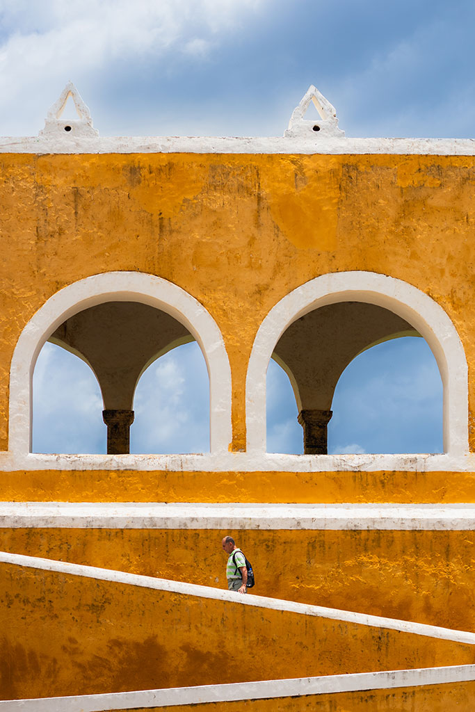 Documentaire foto van een eenzame toerist tegen de achtergrond van gele gebouwen in Izamal, Mexico door reisfotograaf Moments by Mark.
