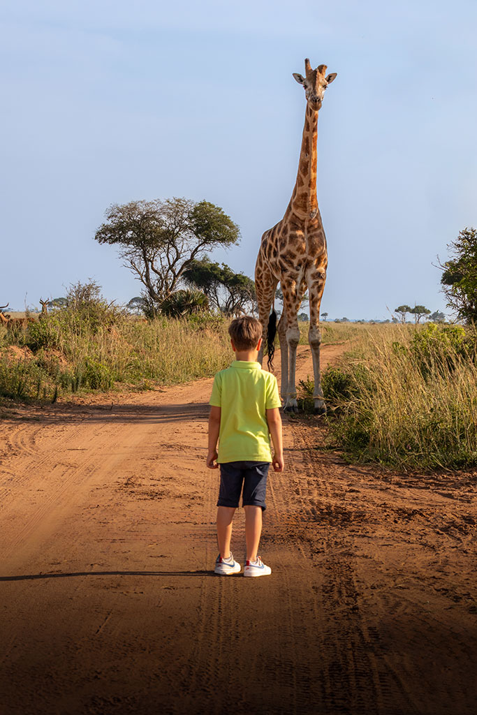 Foto van een ontmoeting van een jongen met een giraf in Oeganda, gemaakt door reisfotograaf Moments by Mark.